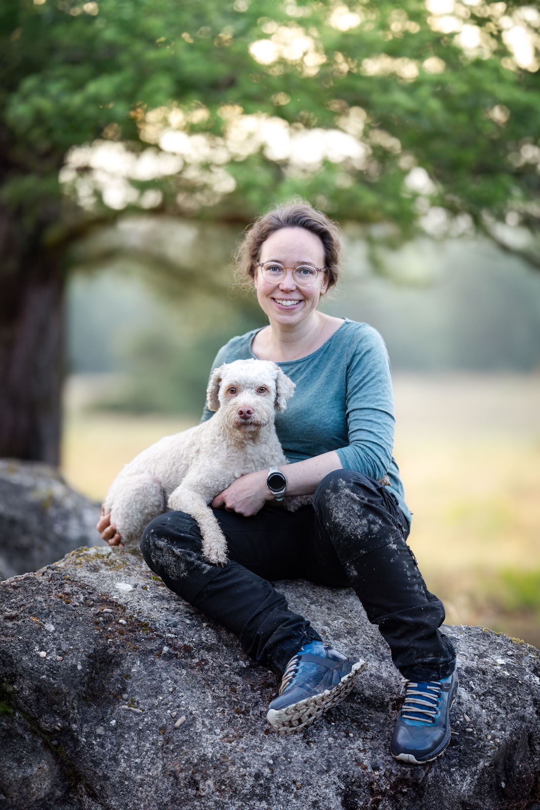 Marina Kern sitzt mit ihrem Hund Maila auf einem Felsen im warmen Abendlicht